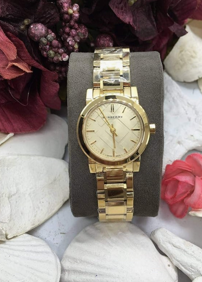 Burberry BU9227 The City women’s watch displayed on branded pillow with stainless steel gold strap and gold dial