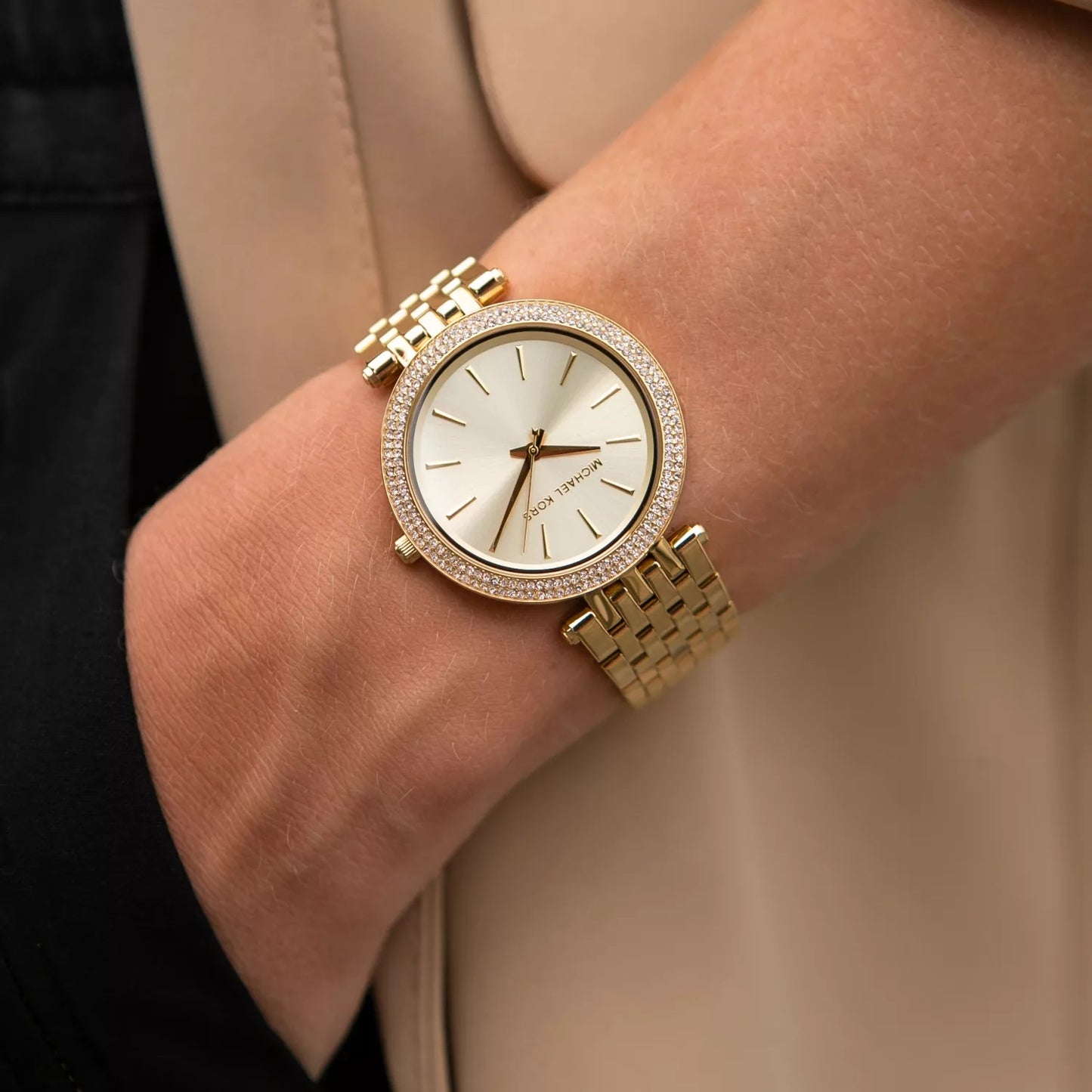 Close-up shot of Michael Kors MK3191 women's watch on wrist, highlighting the gold dial, gold strap, and sparkling crystals
