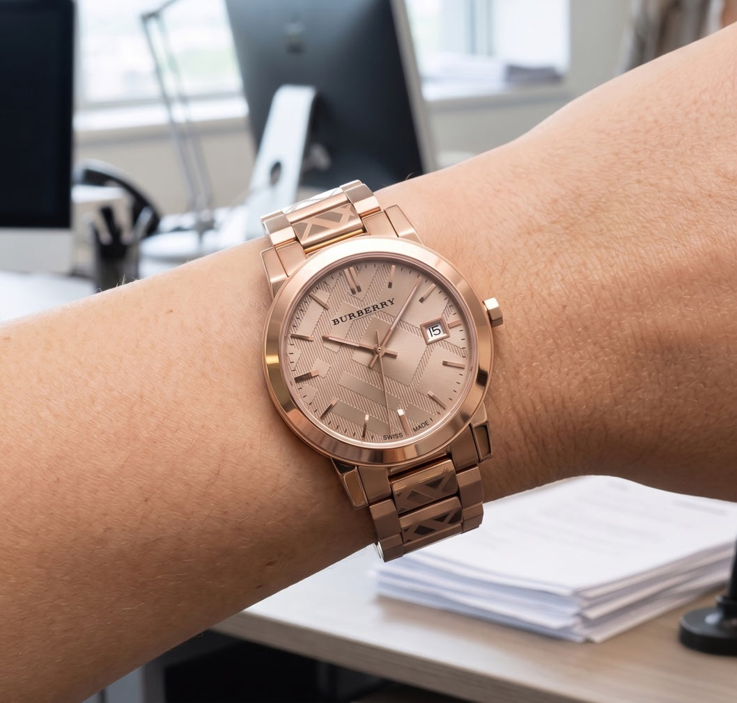 A rose gold Burberry watch with a matching link bracelet worn on a woman's wrist.