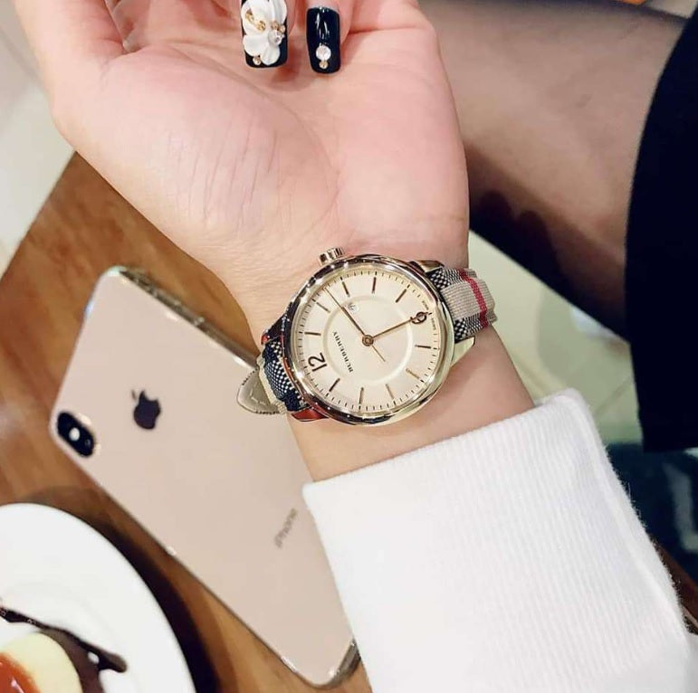 Woman wearing the Burberry BU10104 The City gold watch on her wrist to demonstrate everyday style and elegant fit.