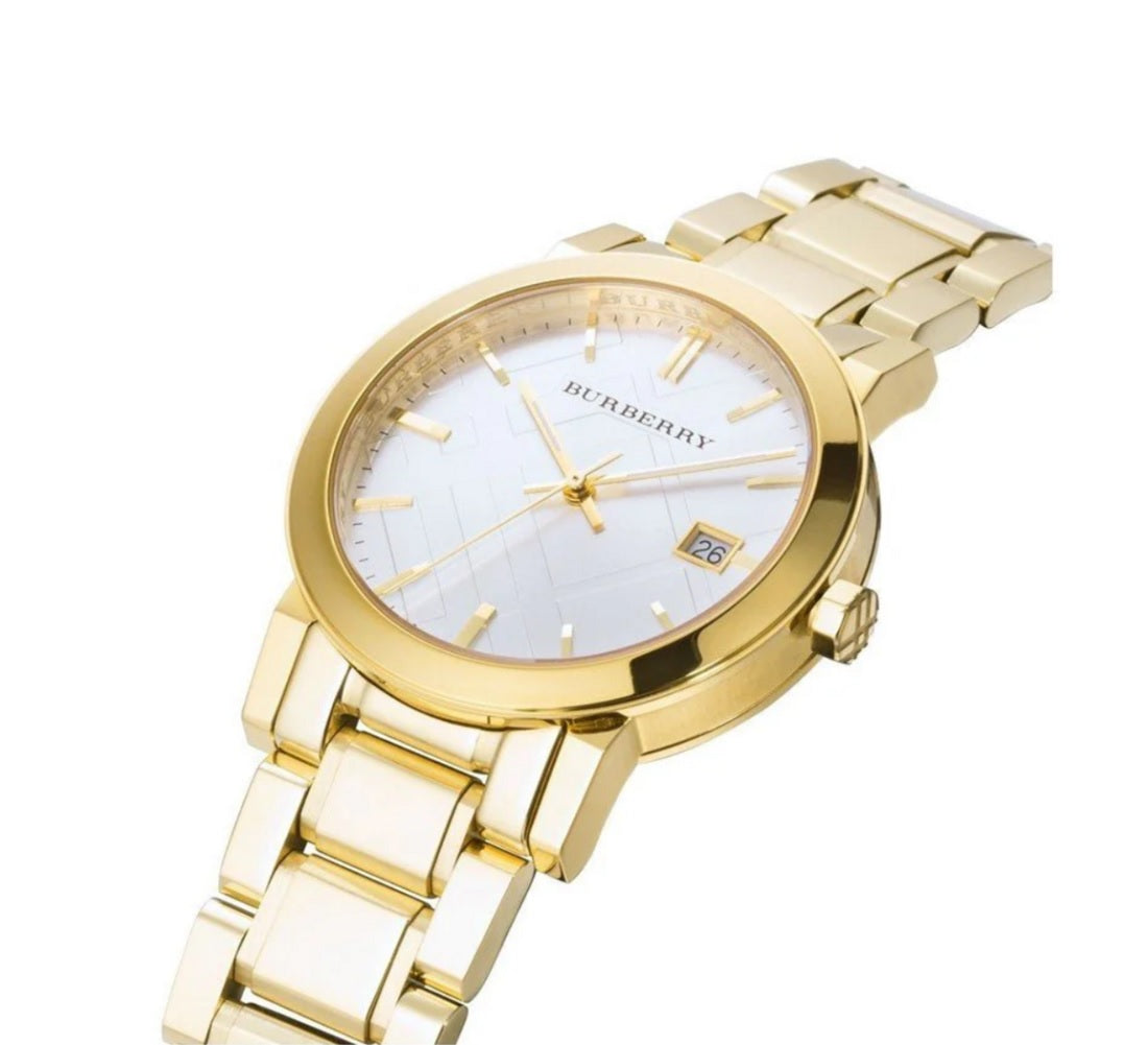 Angled close-up of the Burberry BU9003 gold-tone watch highlighting the signature white check-patterned dial, date display, and polished stainless steel link bracelet.
