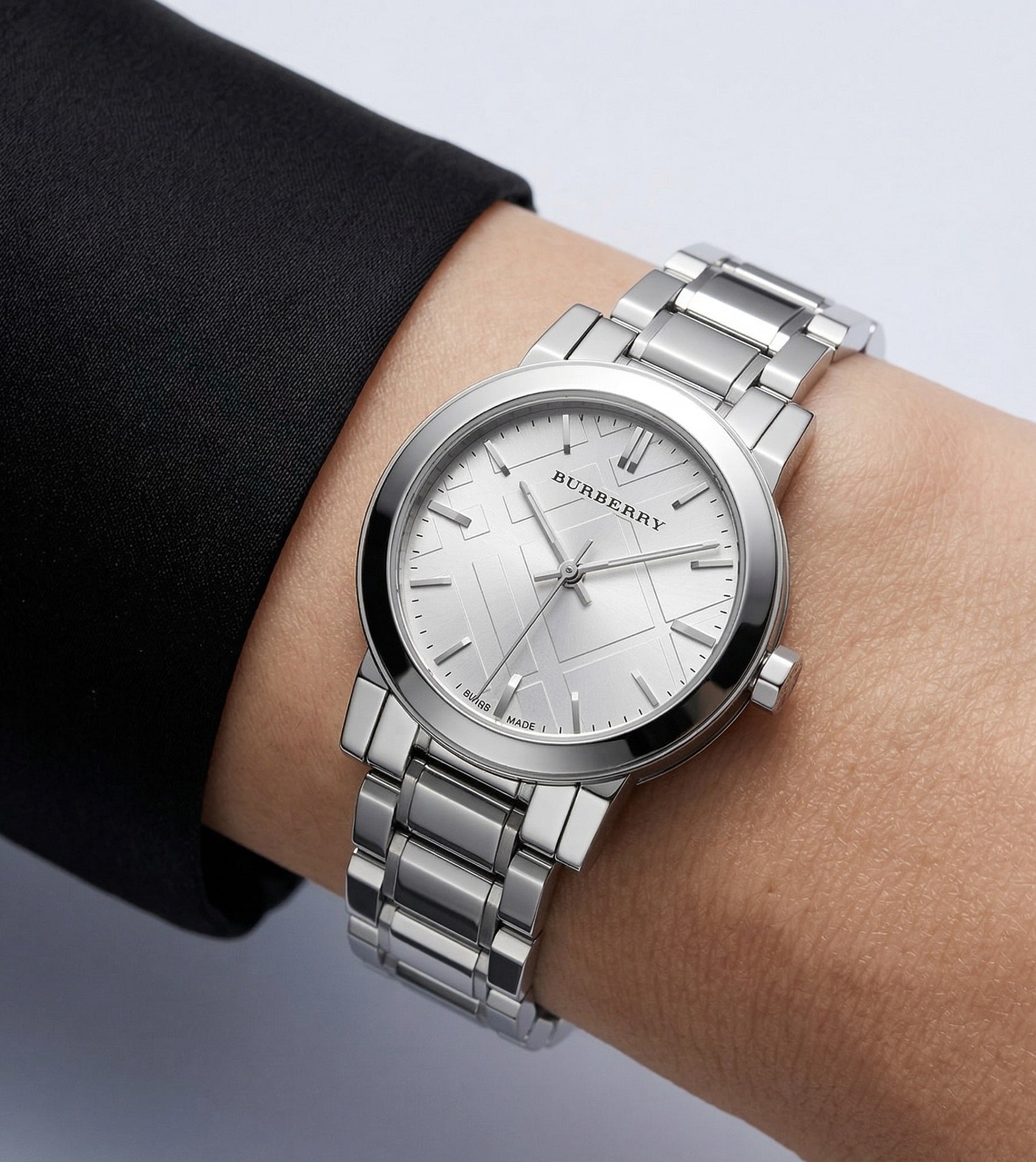 Woman wearing the Burberry BU9223 The City silver watch on her wrist, styled with a black cuff to demonstrate size and everyday fit.