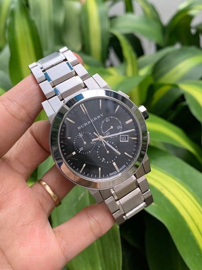 Burberry BU9351 The City men’s watch held in hands showcasing its silver bracelet and black dial