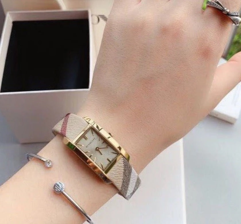 Woman wearing the Burberry BU9509 rectangular gold watch on her wrist to demonstrate everyday style and elegant sizing.