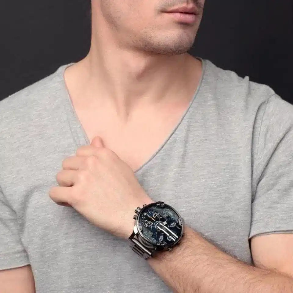 Man wearing the Diesel DZ7331 gunmetal and blue denim watch, styled casually with a grey v-neck t-shirt.