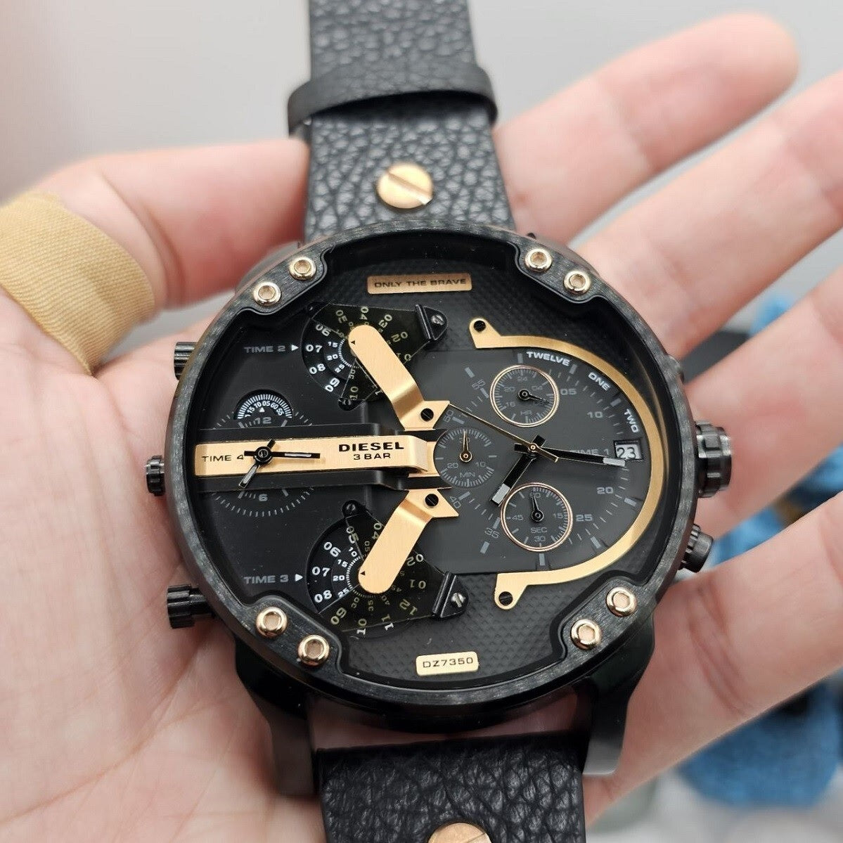 Hand holding the oversized Diesel DZ7350 black and rose gold watch to demonstrate scale, finish, and intricate dial details.