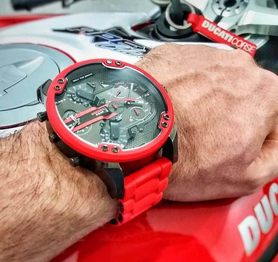 Man wearing the bold Diesel DZ7370 red silicone watch on his wrist while resting his hand on a motorcycle, highlighting its sporty and aggressive styling.