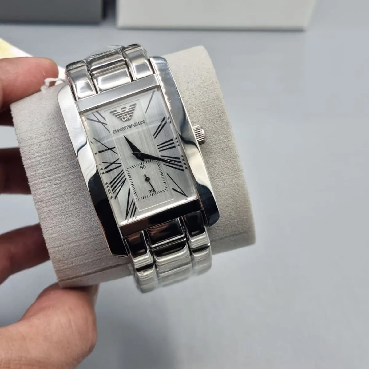 Emporio Armani AR0145 men’s rectangular watch displayed on a branded pillow, emphasizing luxury and sophistication