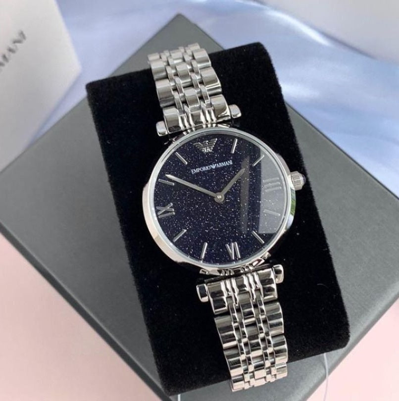 Emporio Armani AR11091 Gianni T-Bar displayed on branded pillow with silver strap and blue dial
