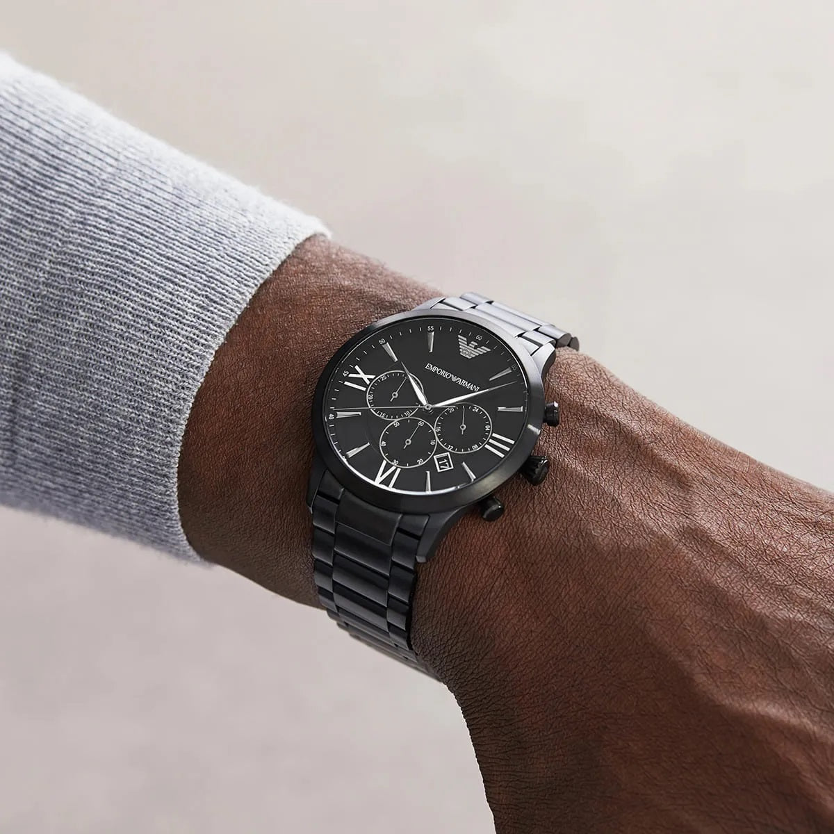Man wearing the Emporio Armani AR11349 black chronograph on his wrist, styled with a grey sweater to show its sophisticated everyday aesthetic.