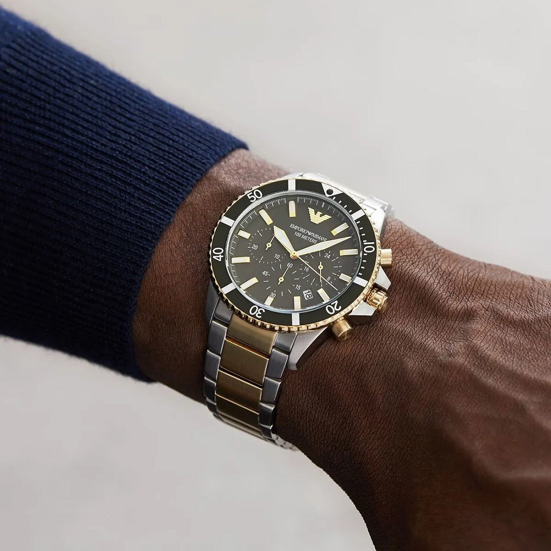 Lifestyle image of a man wearing the Emporio Armani AR11361 two-tone diver watch on his wrist, styled with a dark blue cuff.