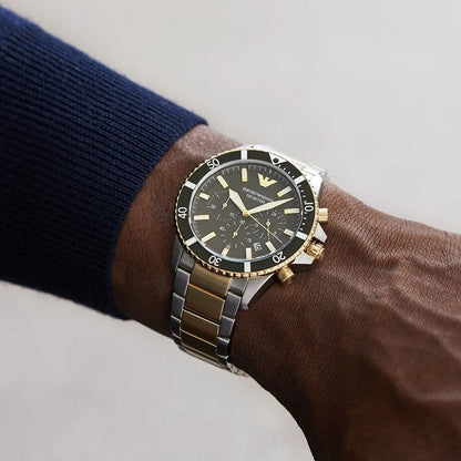 Lifestyle image of a man wearing the Emporio Armani AR11361 two-tone diver watch on his wrist, styled with a dark blue cuff.