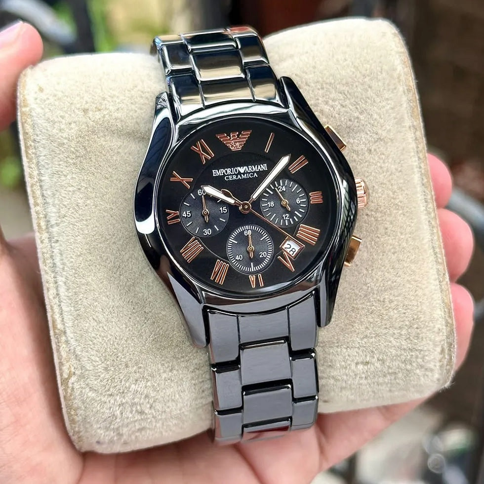 Emporio Armani AR1411 women's watch displayed on a branded pillow, showcasing the black ceramic strap and rose gold tone