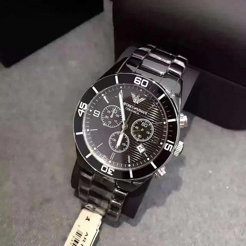 Emporio Armani AR1421 displayed on a branded pillow, showcasing the black ceramic strap and black chronograph dial