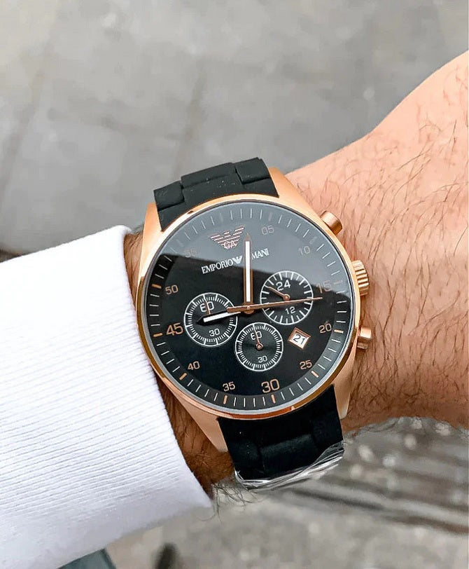 Close-up wrist shot of Emporio Armani AR5905 with black dial, rose gold case, and black silicone strap