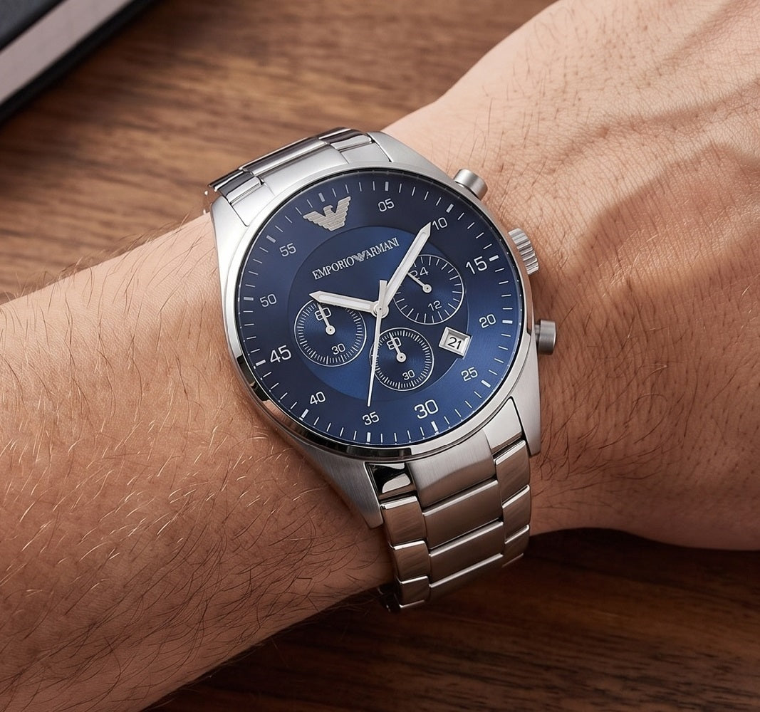 A silver stainless steel wristwatch with a blue dial and silver bracelet, worn on a man's wrist.