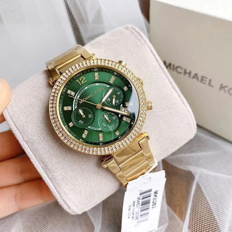 Michael Kors MK6263 Parker gold and green watch resting on a retail display cushion with tags, showing its elegant presentation.