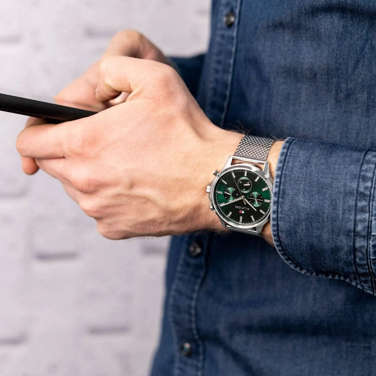 Man wearing the Tommy Hilfiger 1710499 Ryder green dial watch on his wrist, styled with a denim shirt to show scale and daily wear fit.
