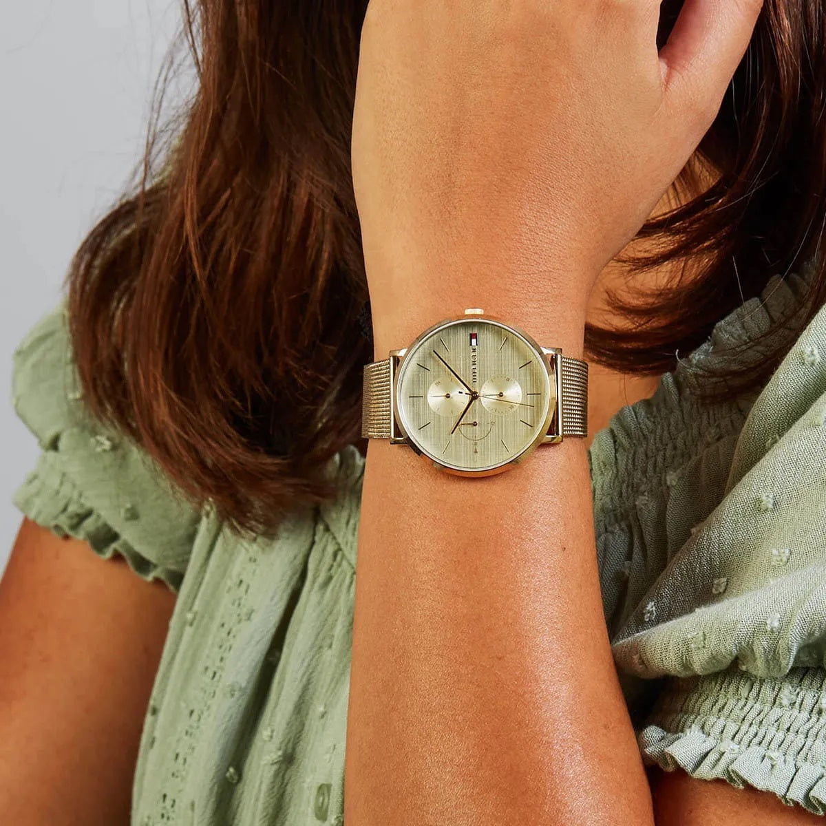 Tommy Hilfiger 1781943 women’s watch worn on wrist with gold mesh strap and gold dial