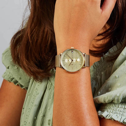 Tommy Hilfiger 1781943 women’s watch worn on wrist with gold mesh strap and gold dial