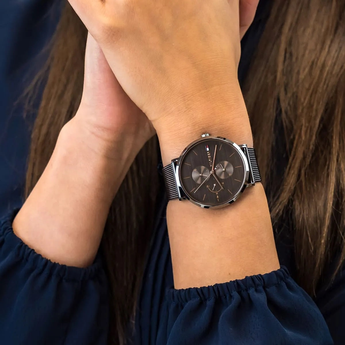 Close-up of Tommy Hilfiger 1781945 women’s grey mesh strap watch worn on wrist, with focus on the grey dial